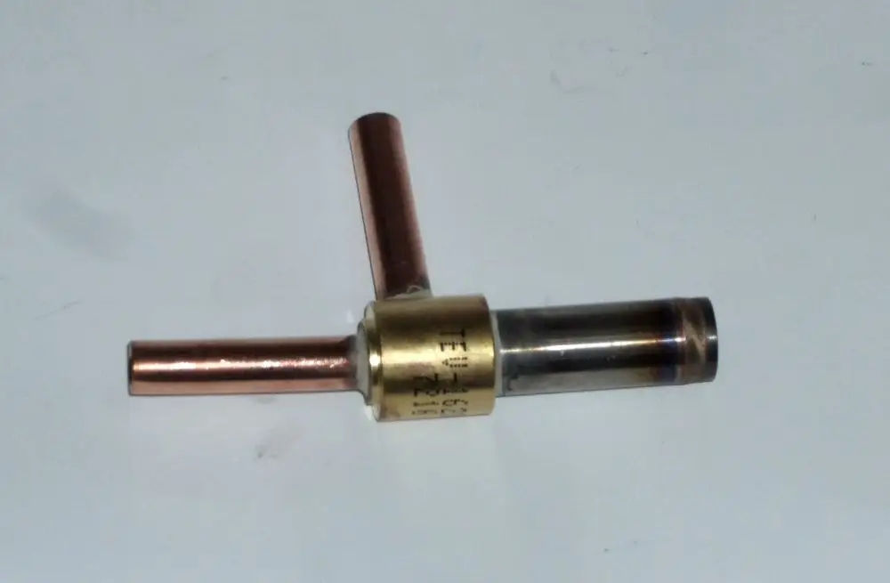 Magnetischer Ventilkörper von Daikin mit zwei Kupferanschlüssen und einem zylindrischen Gehäuse, das auf einem weißen Untergrund platziert ist.